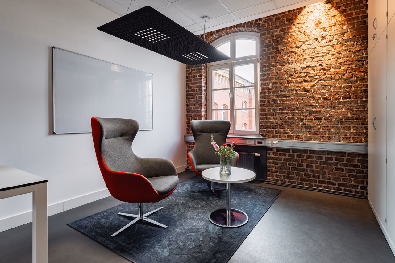 Sitzecke mit rotem Sessel vor Backsteinwand