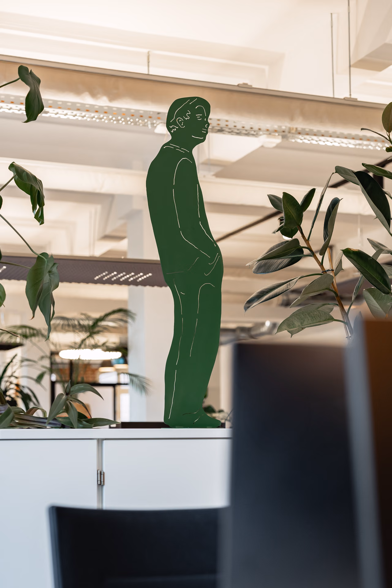 Grüne Figur zwischen Pflanzen im Loft