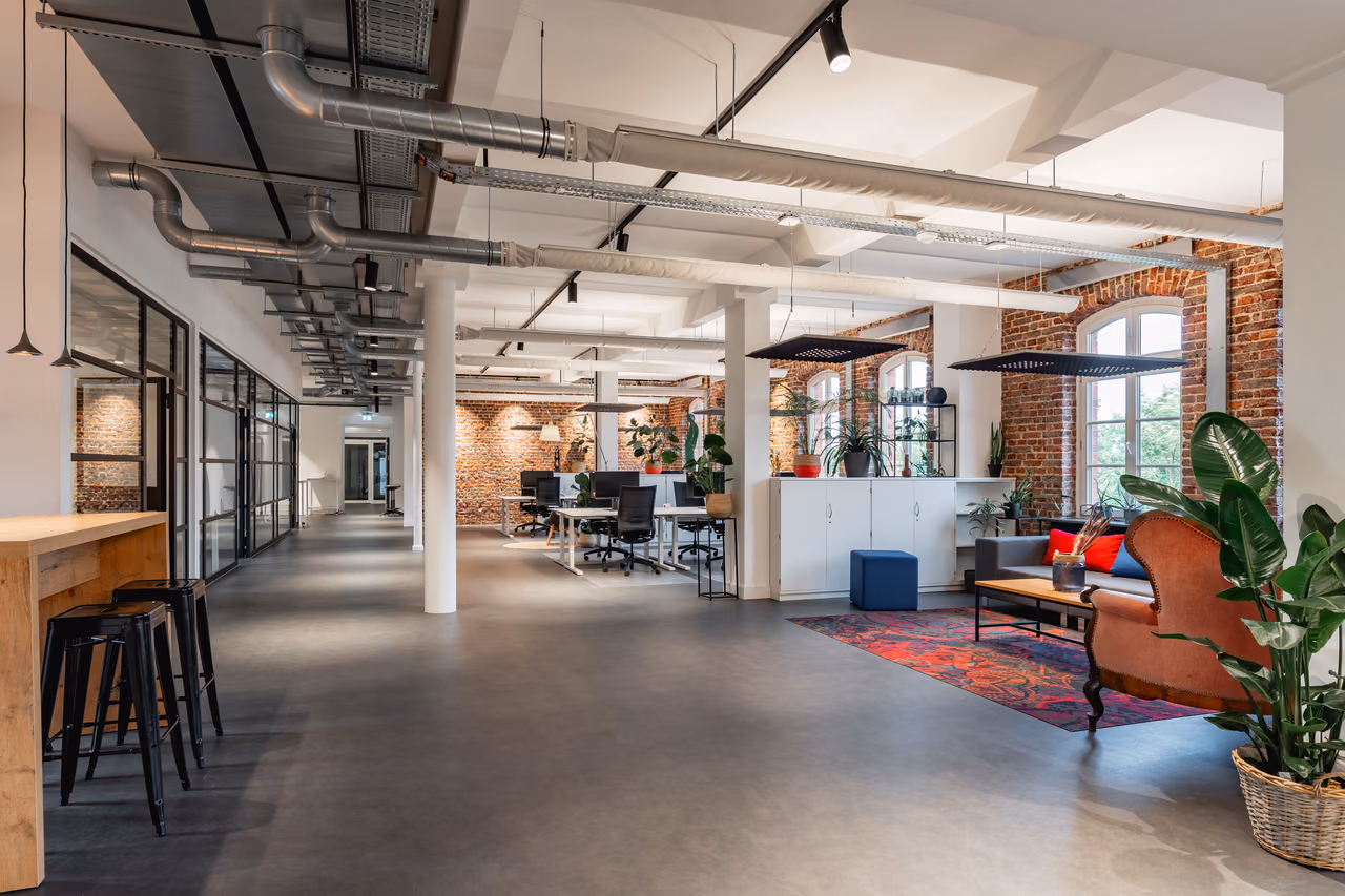 Loft von StartMiUp Minden mit Bar, Arbeitsplätzen, Backsteinwand und Lounge mit rotem Teppich